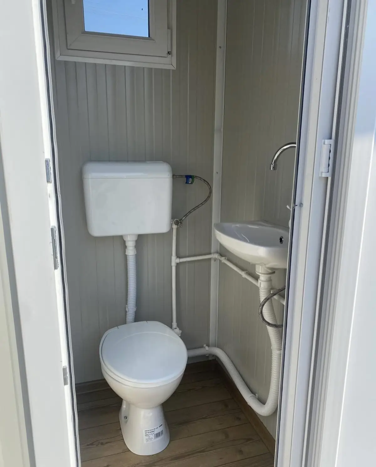 Interior of a deluxe flushing porta potty with white flush toilet, sink and soap dispenser