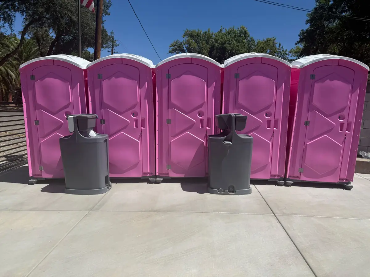Two gray Bravo hand wash stations in front of a row of pink porta potties