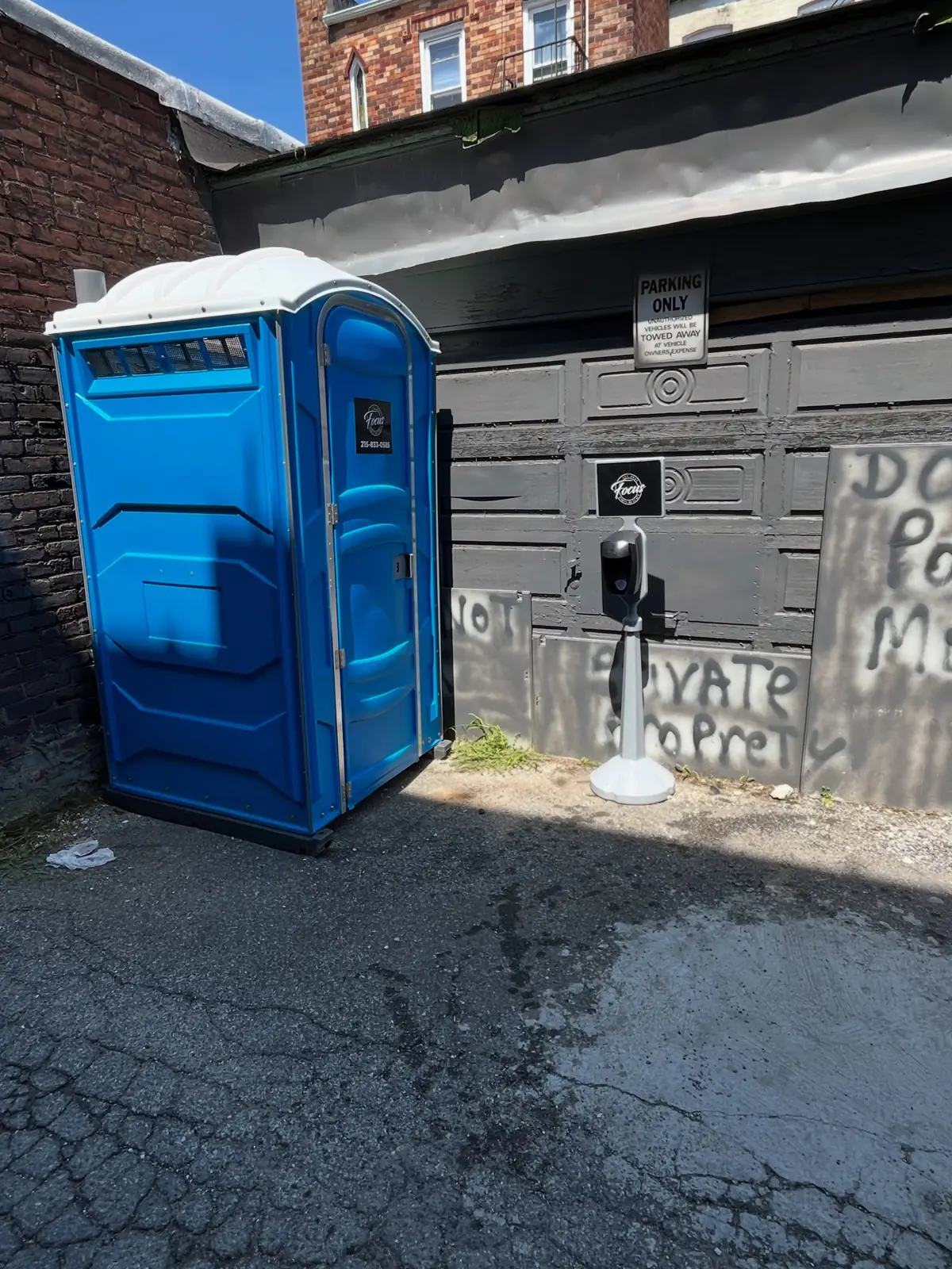 Blue PolyJohn PJN3 standard porta potty in a paved alley in downtown Bethlehem