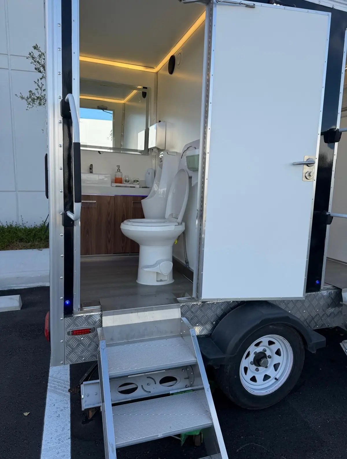 Restroom trailer station interior seen from the entry steps with wood-tone cabinet and porcelain toilet